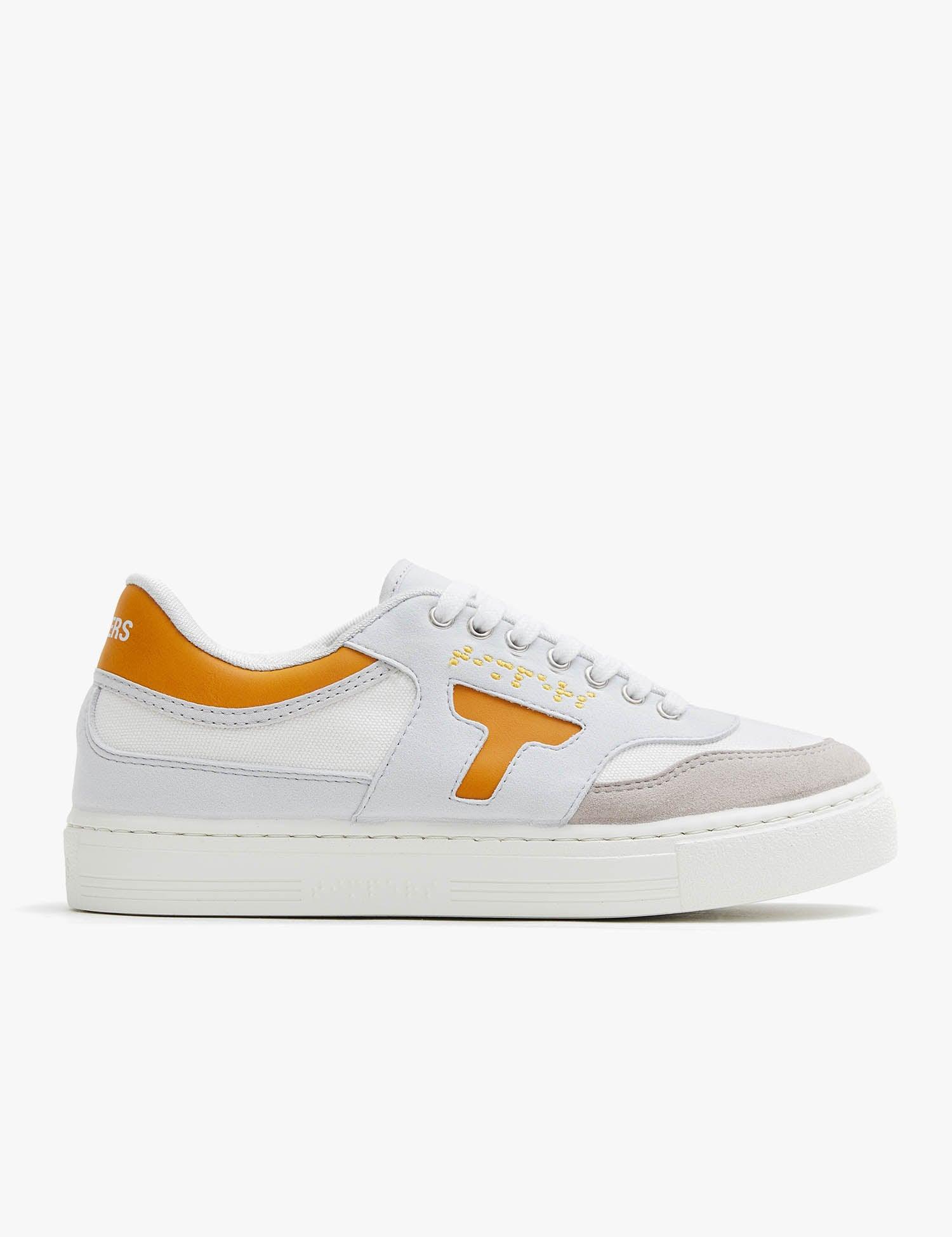 Zapatilla de hombre y mujer. Zapatilla unisex. Zapatilla de estilo más deportivo. El color que predomina es el mostaza y blanco .La zapatilla tiene detalles en blanco. Los cordones son color blanco al igual que la suela.