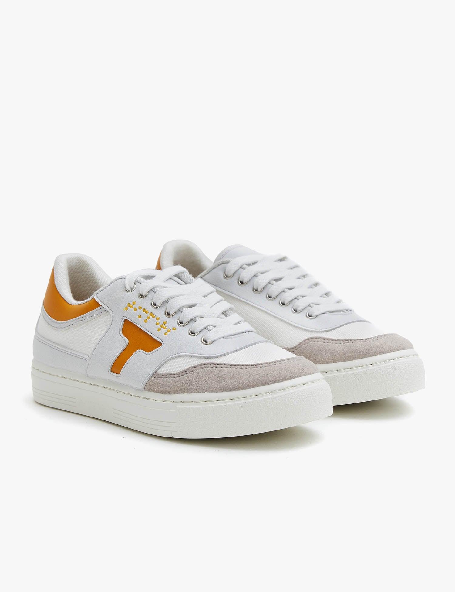 Zapatilla de hombre y mujer. Zapatilla unisex. Zapatilla de estilo más deportivo. El color que predomina es el mostaza y blanco .La zapatilla tiene detalles en blanco. Los cordones son color blanco al igual que la suela.