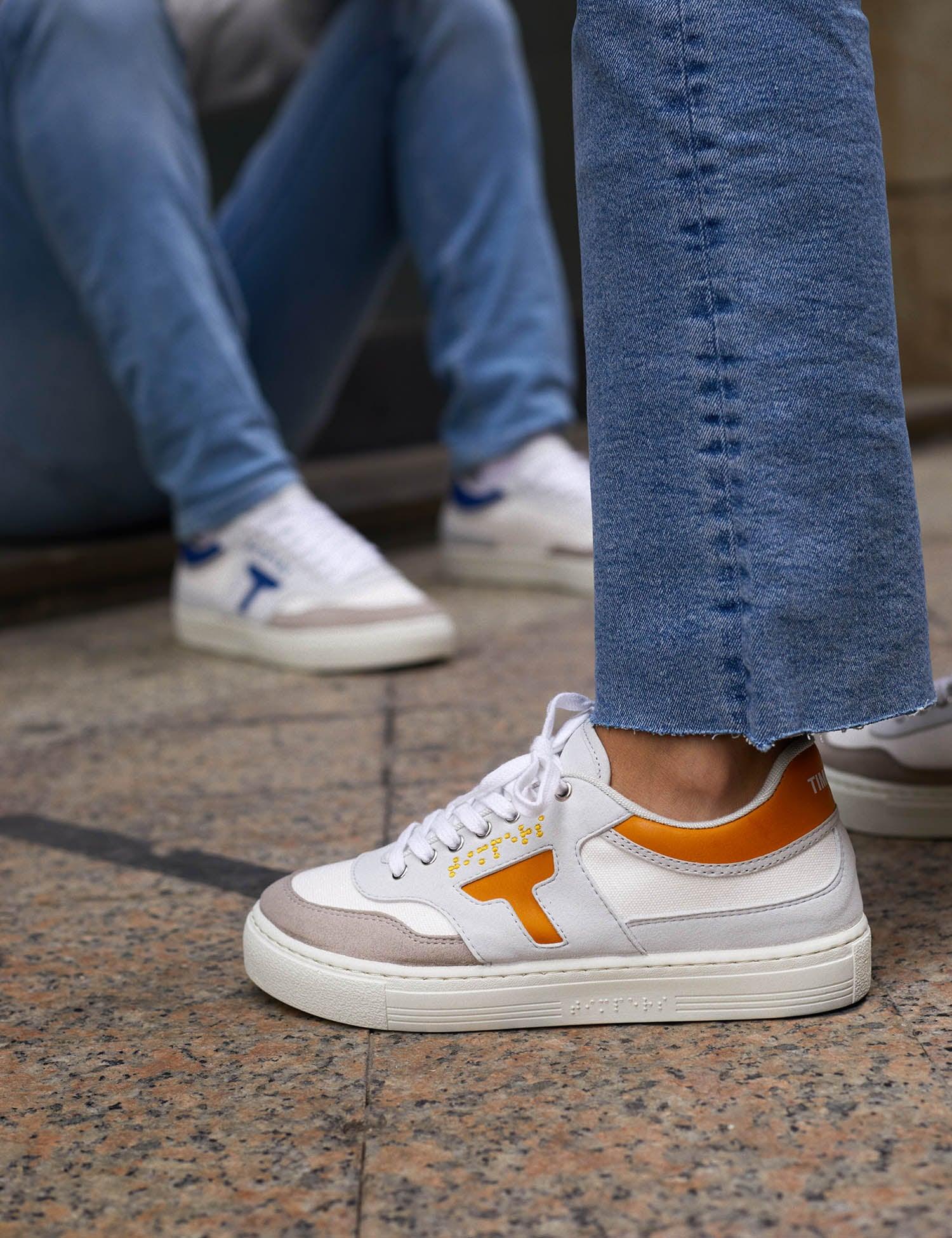 Zapatilla de hombre y mujer. Zapatilla unisex. Zapatilla de estilo más deportivo. El color que predomina es el mostaza y blanco .La zapatilla tiene detalles en blanco. Los cordones son color blanco al igual que la suela.