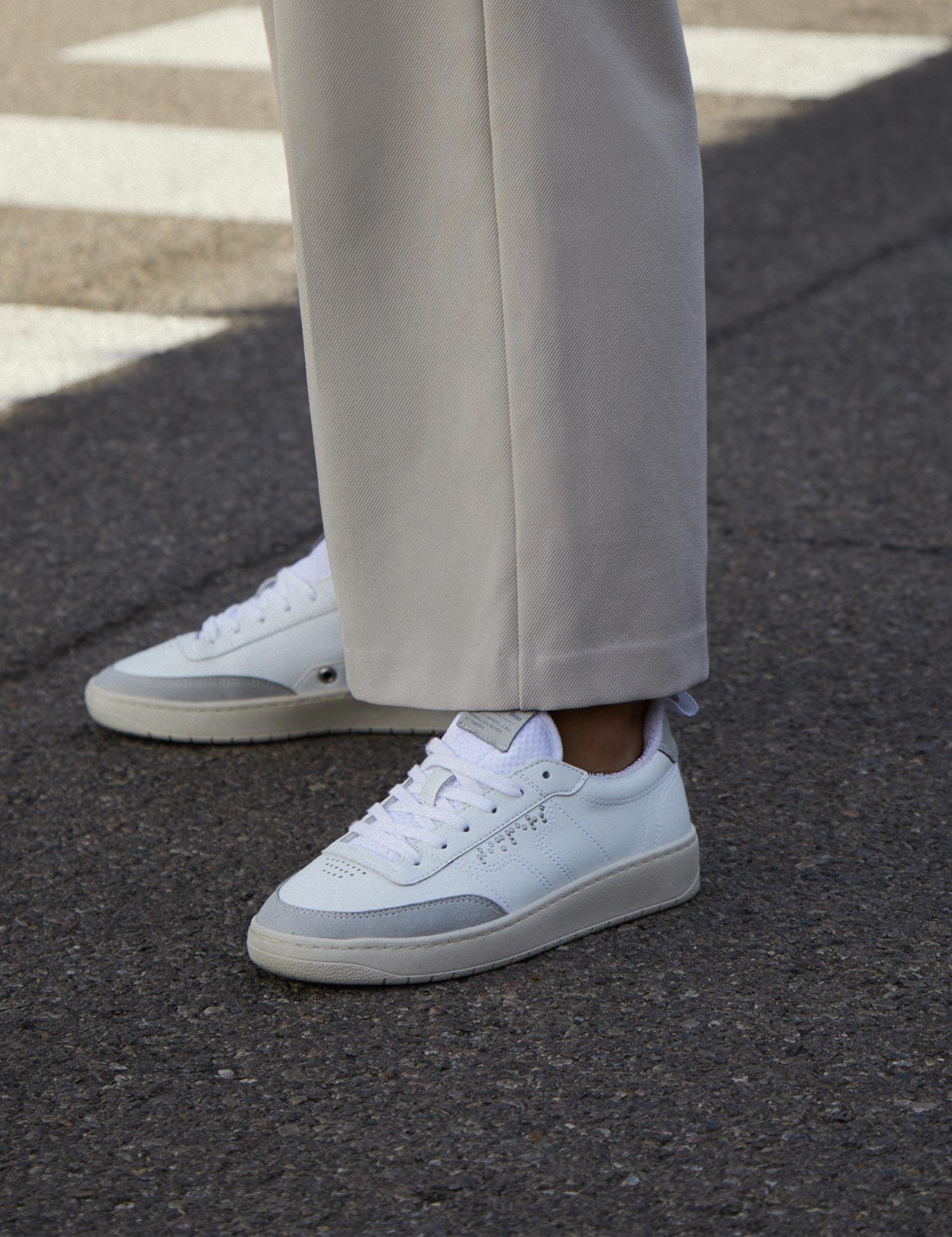 Zapatilla blanca con suela un tono color crema con puntera y trasera gris. Son zapatillas unisex.